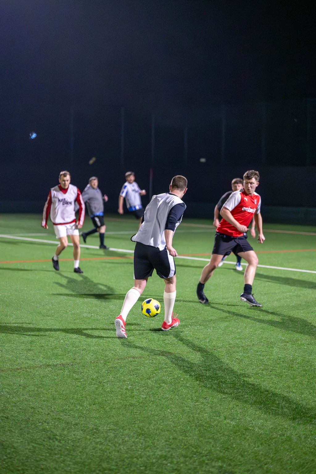 Mixed-ability adults playing football under floodlights